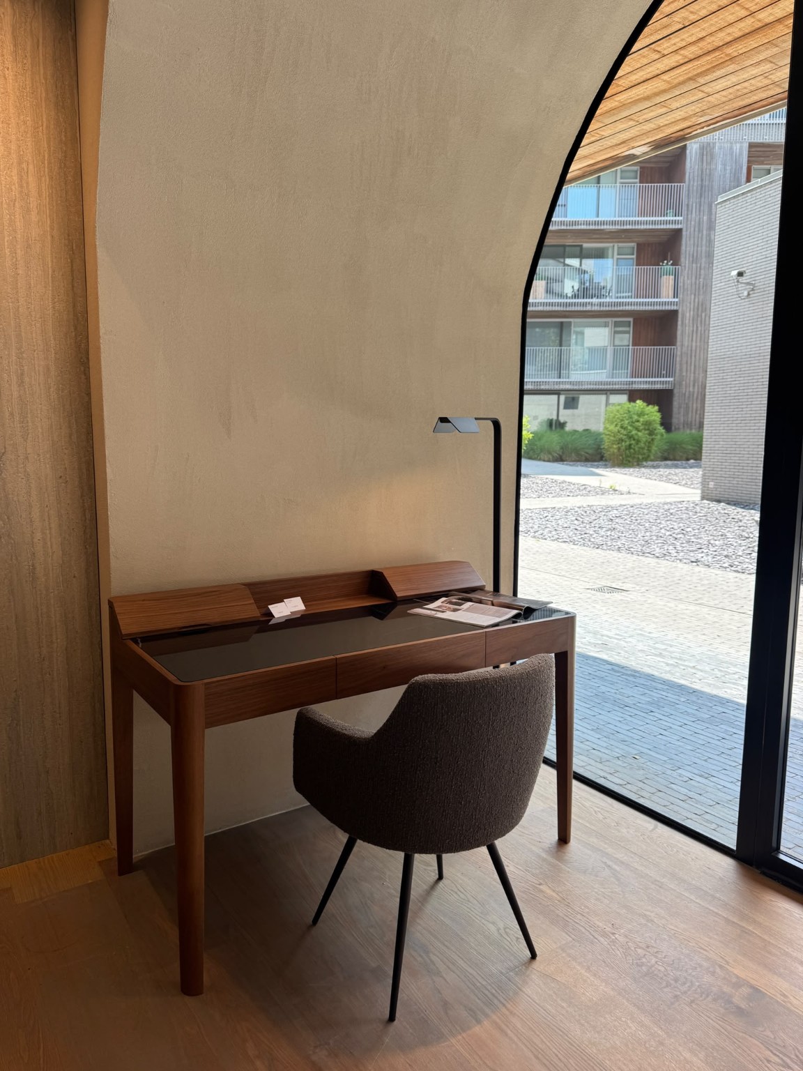 Compact houten bureau op maat bij een hoge raampartij